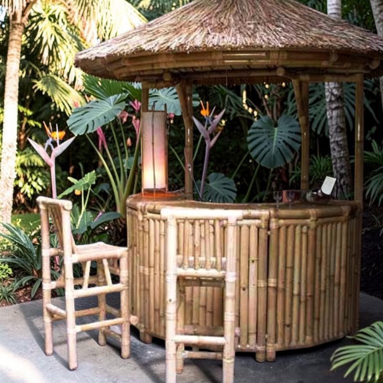 Bar Paillote en Bambou Bar en bambou avec toit de chaume, entouré de plantes tropicales.